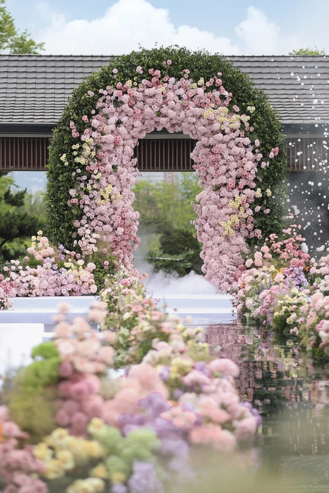 A Dreamlike Pink Garden Wedding with a Floral Arch and Reflective Water Aisle
