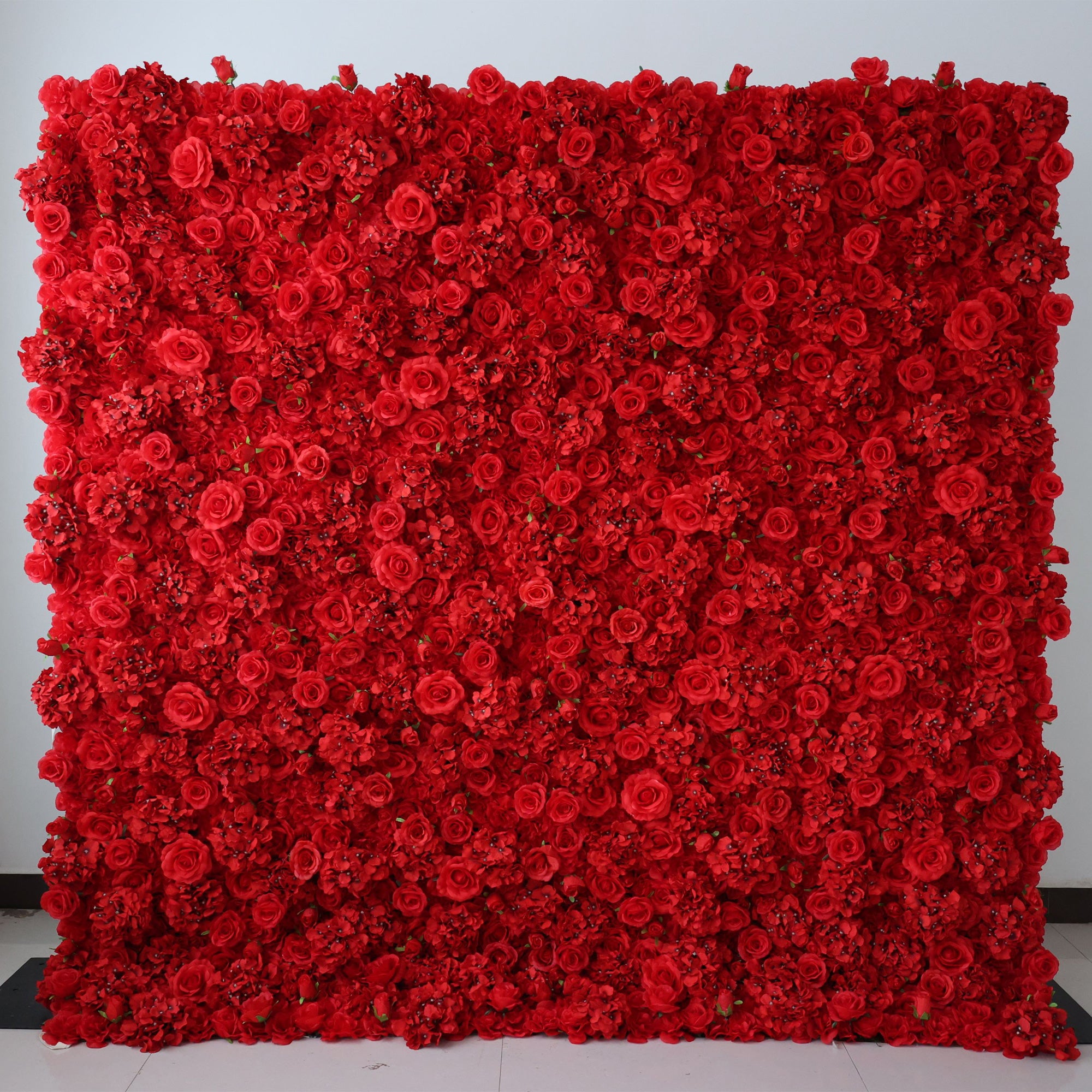 A large square backdrop featuring a dense arrangement of red artificial roses, creating a rich and vibrant floral wall.