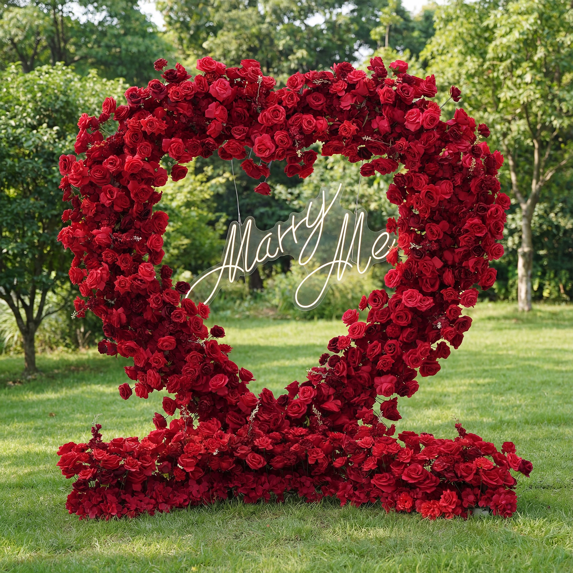 Heart-shaped arrangement of red roses with 'Marry Me' inscription on grass