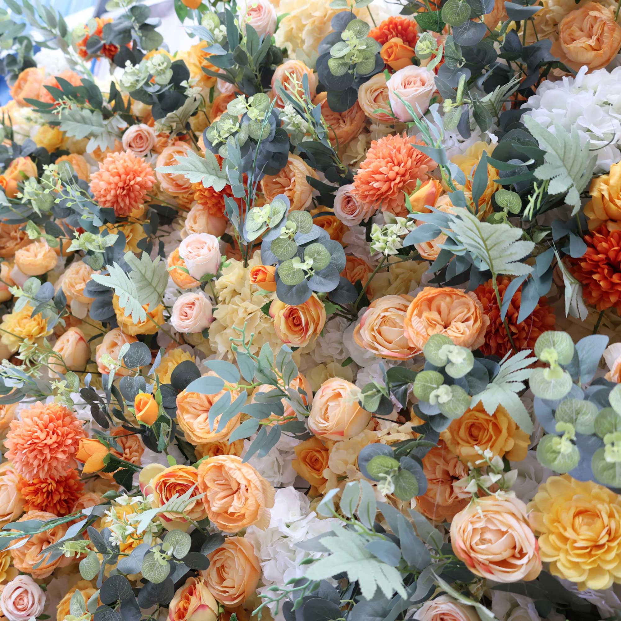 Handcrafted autumn-themed 5D artificial flower wall backdrop featuring vibrant shades of orange, yellow, beige, and green, set outdoors against a natural background. Ideal for weddings, events, and celebration decor, adding a warm, seasonal touch.VF-401-4