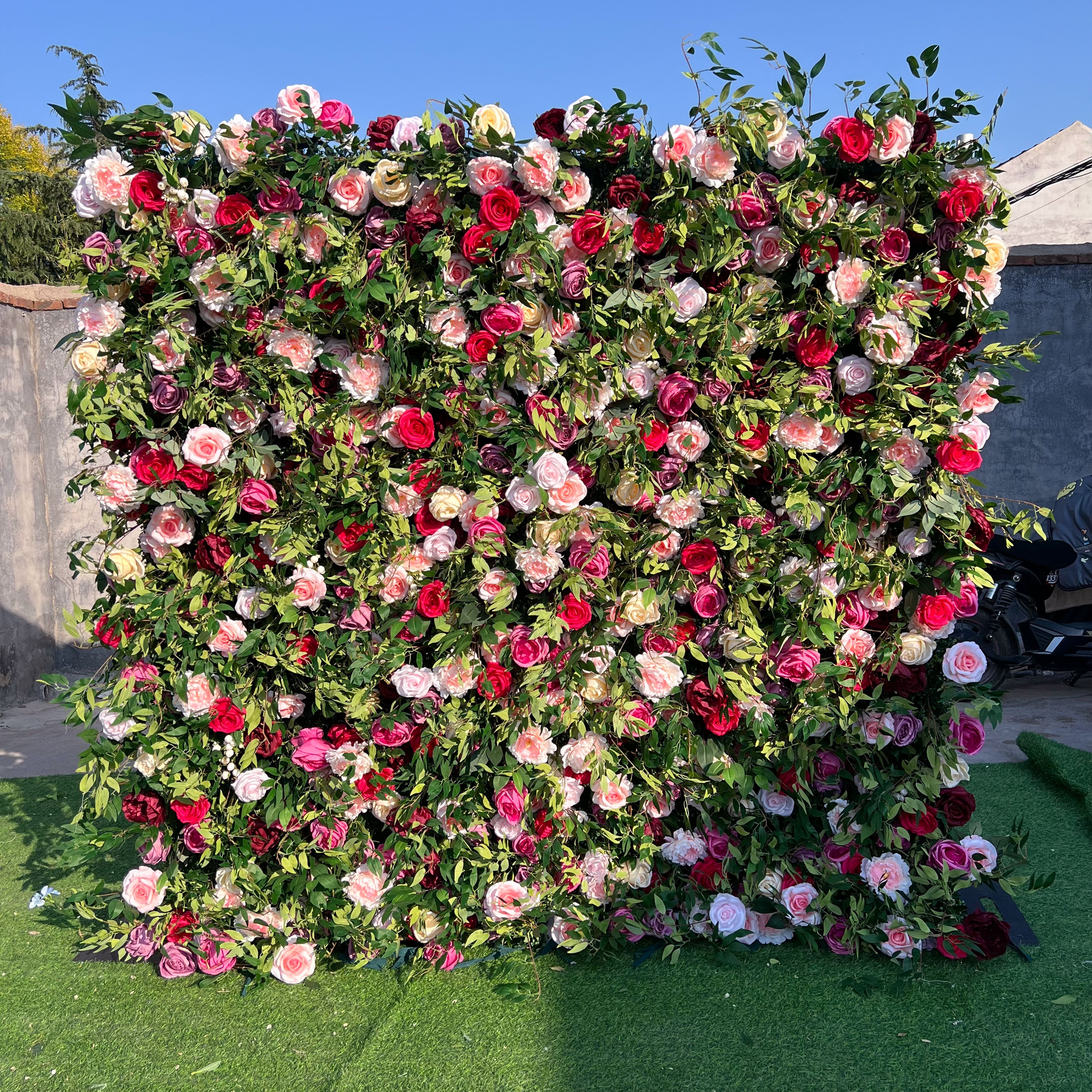 Artificial rose wall with a dense mix of vibrant colors and greenery, offering a beautiful and dramatic backdrop for weddings and special occasions.
