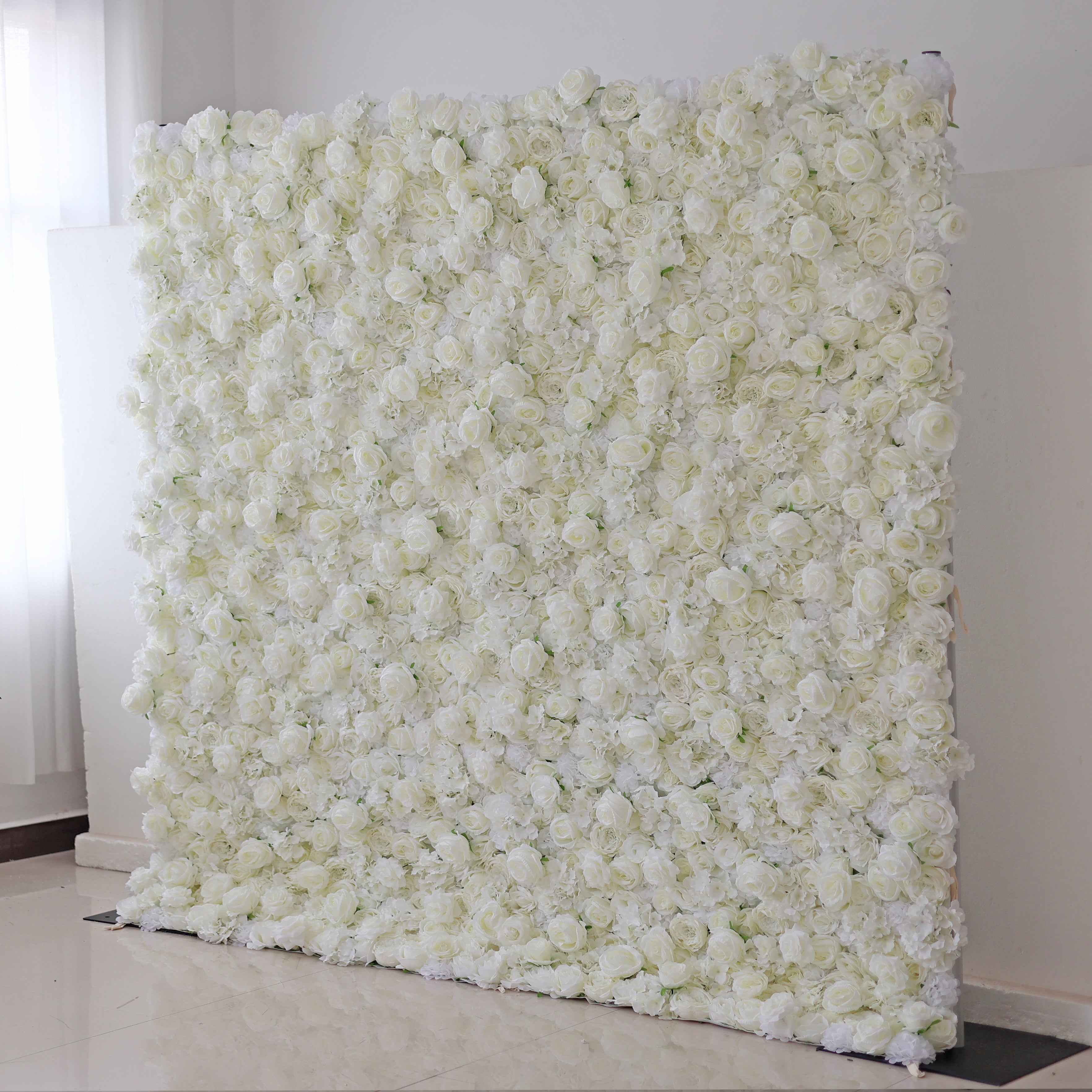 A roll-up fabric artificial white flower wall used as a backdrop.