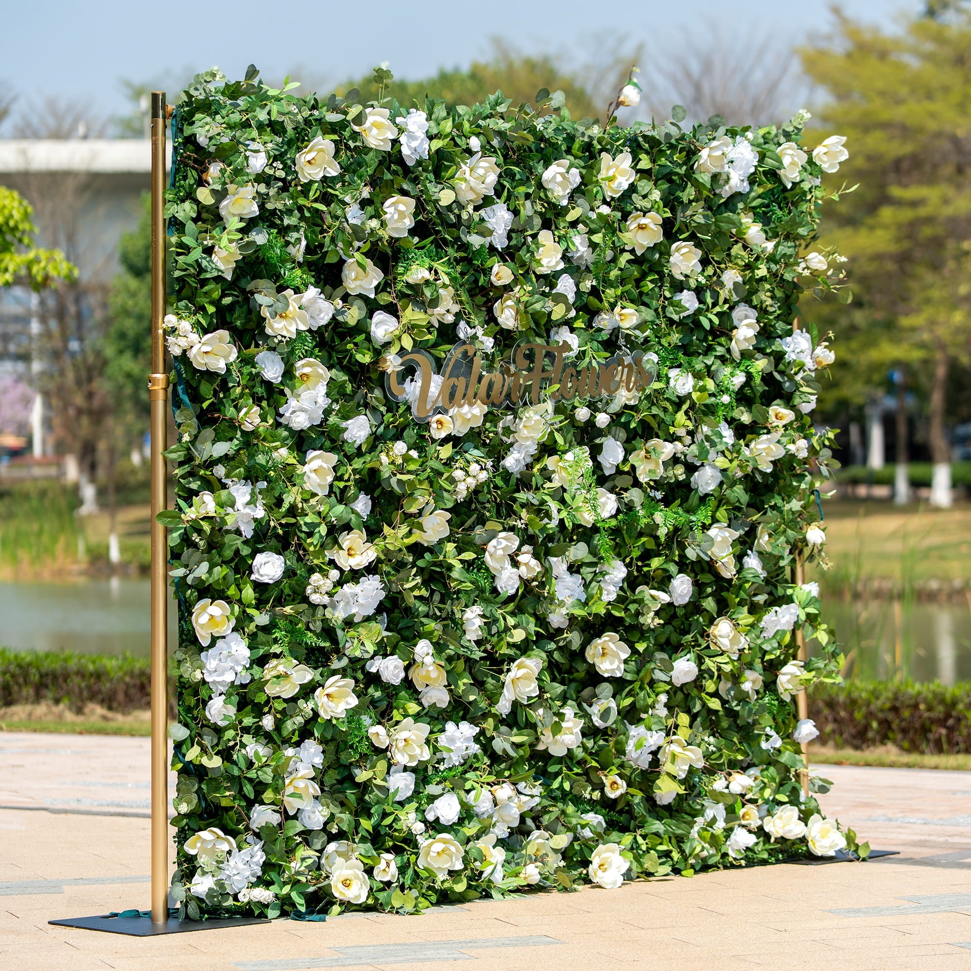 This backdrop is a verdant floral wall supported by golden - hued poles. It is densely packed with artificial green foliage interspersed with white roses and other white blooms. The "Valar Flowers" sign in elegant script adds a touch of sophistication.
The color scheme features a striking contrast between the lush green leaves and the pure white flowers, creating a fresh and natural style. Ideal for events like weddings, corporate gatherings, or garden - themed parties.