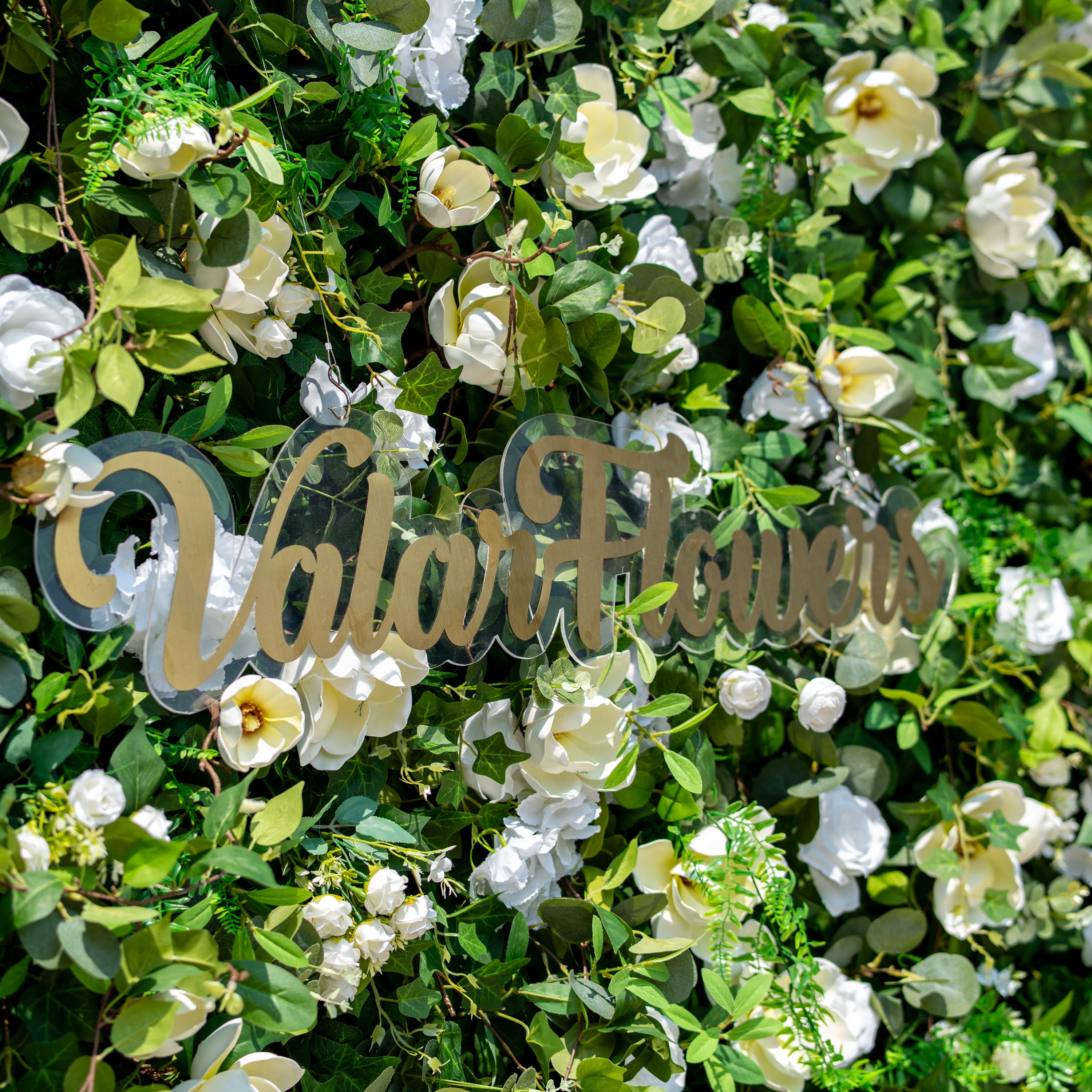 This backdrop is a lush floral arrangement featuring a mix of white roses and large, magnolia - like white blooms, set against a dense bed of green foliage that includes various types of leaves like eucalyptus.
A golden - hued "Valar Flowers" sign is prominently displayed. The color scheme combines fresh green and pure white, creating a natural, elegant style, perfect for events such as weddings, corporate functions, or garden parties.
