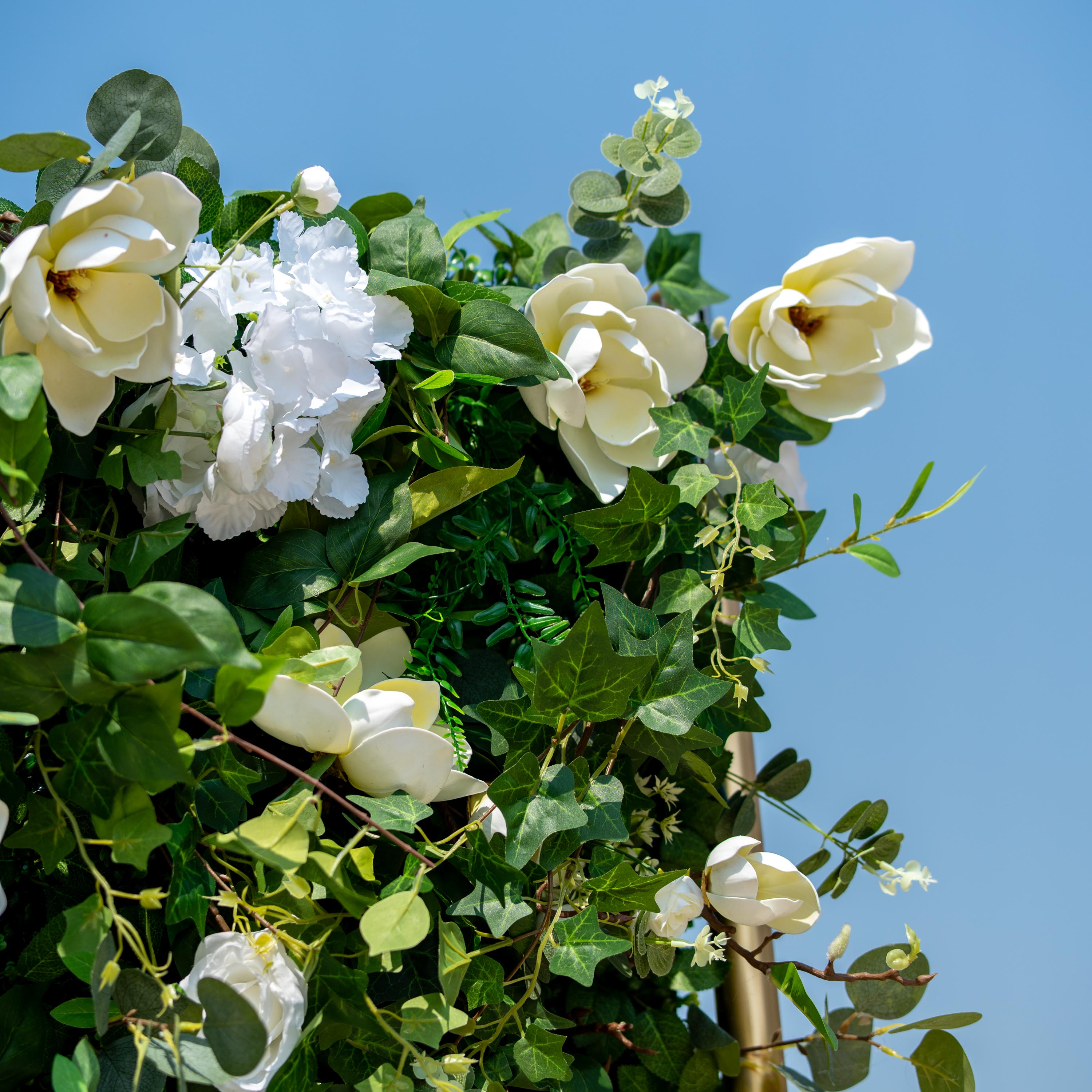 This backdrop showcases a lush arrangement of artificial greenery interspersed with white flowers. Prominent flowers include large, magnolia - like blooms, delicate white roses, and clusters of white hydrangeas.
The greenery features a mix of eucalyptus - style leaves and various types of ivy - like foliage. The color palette of green and white creates a fresh, natural, and elegant style, ideal for events seeking a serene and sophisticated ambiance.