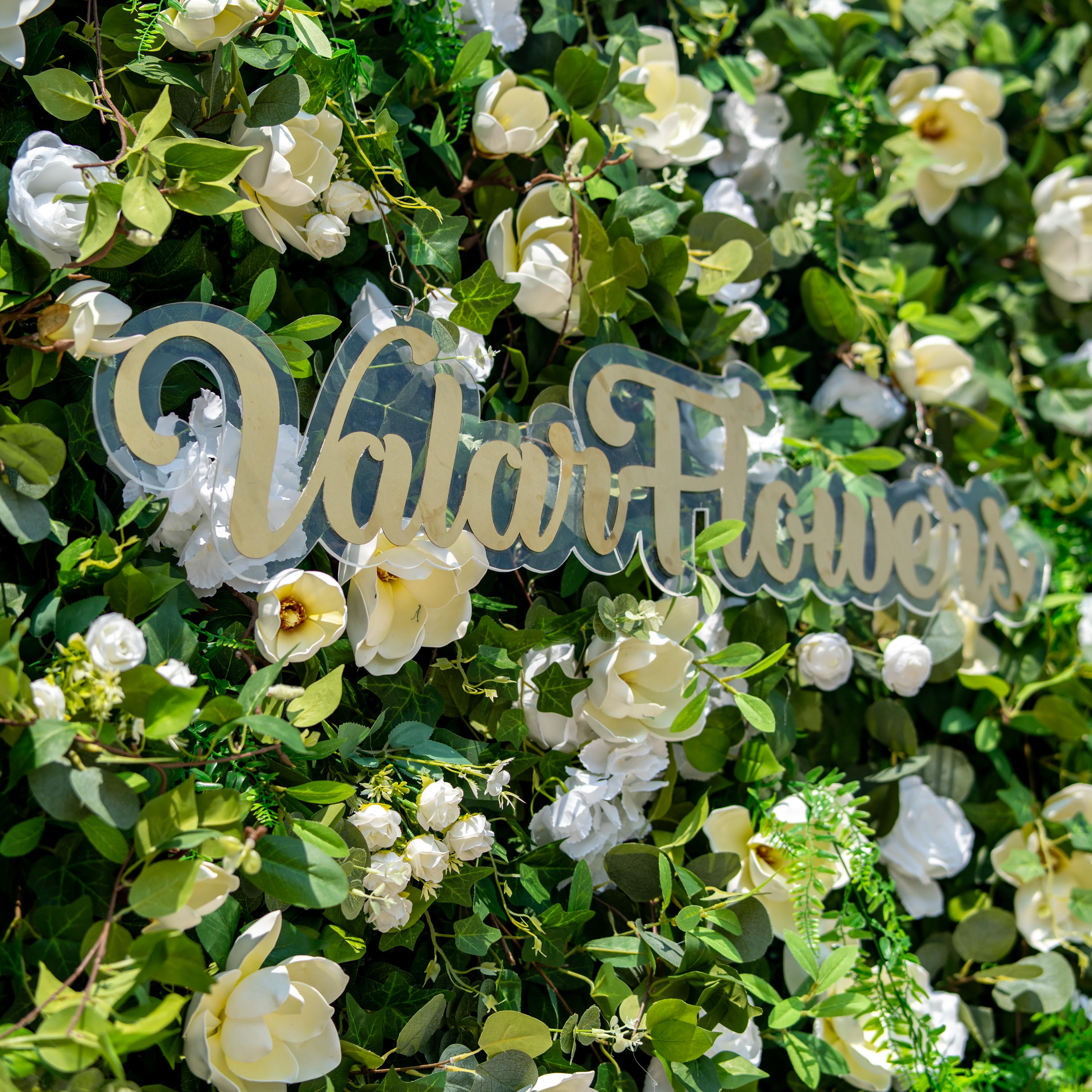 This backdrop showcases a lush floral wall with artificial greenery and white flowers. It features magnolia - like blooms, white roses, and hydrangea - like clusters. The colors are predominantly green and white.
A sign with “Valar Flowers” adds an elegant touch. The style is natural and sophisticated, ideal for events seeking a fresh, garden - inspired aesthetic.