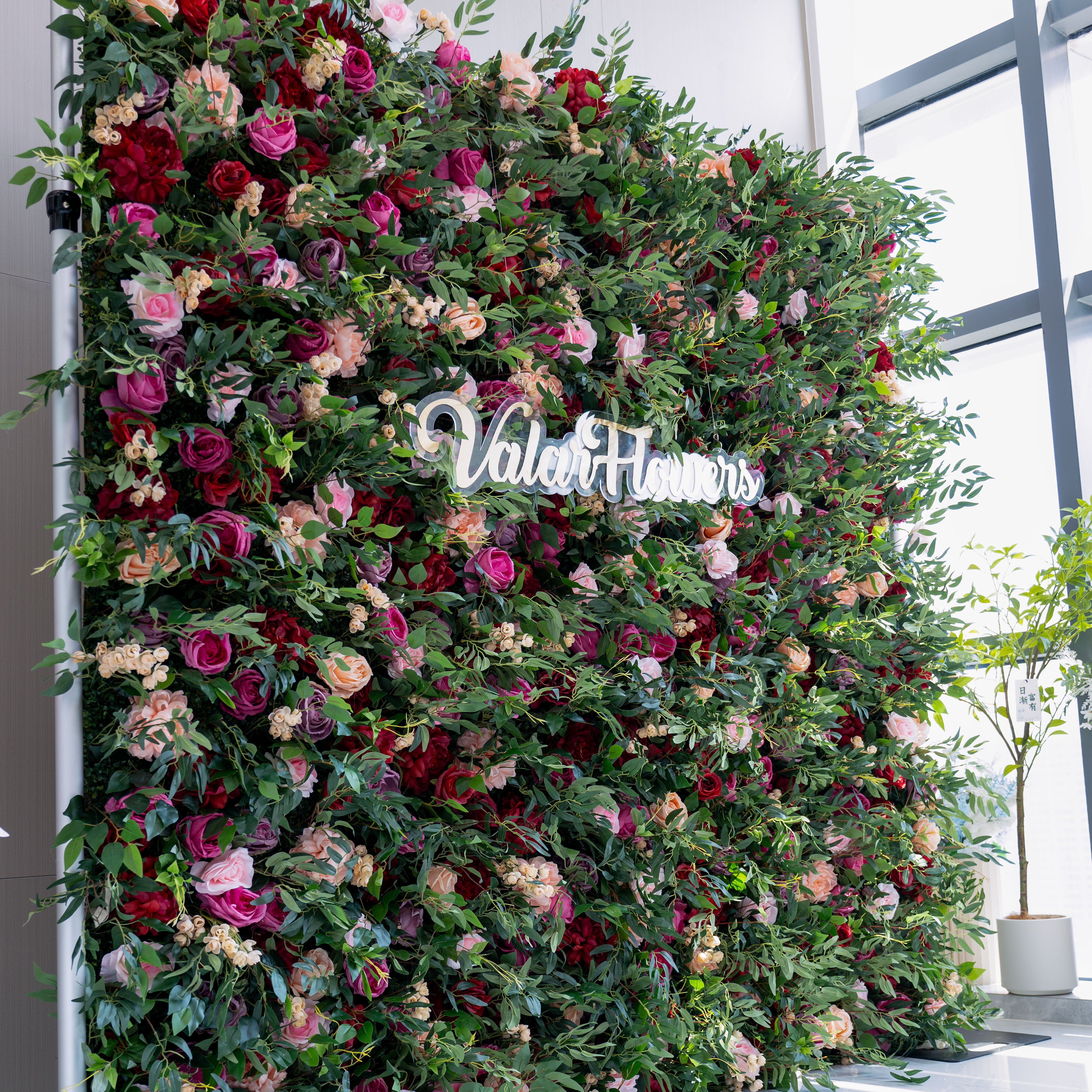 Elegant multi-colored rose flower wall with shades of red, pink, and green foliage, designed to add a luxurious touch to any event setting.