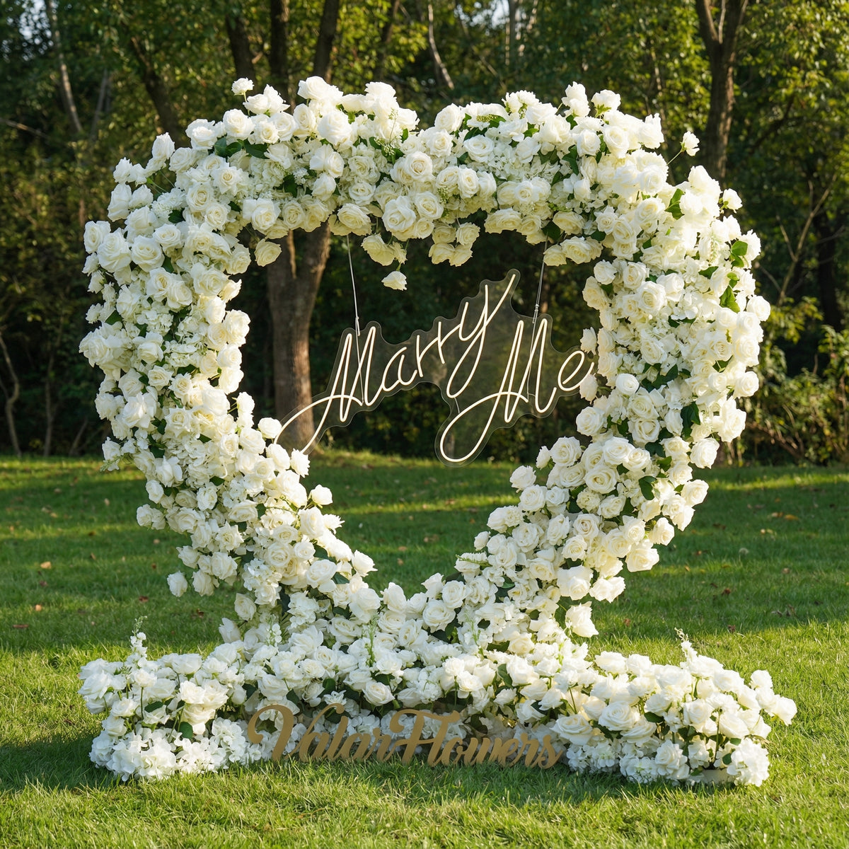 Floral arch with 'Mary Me' and 'Flower Planners' text on a grassy area with trees in the background.
