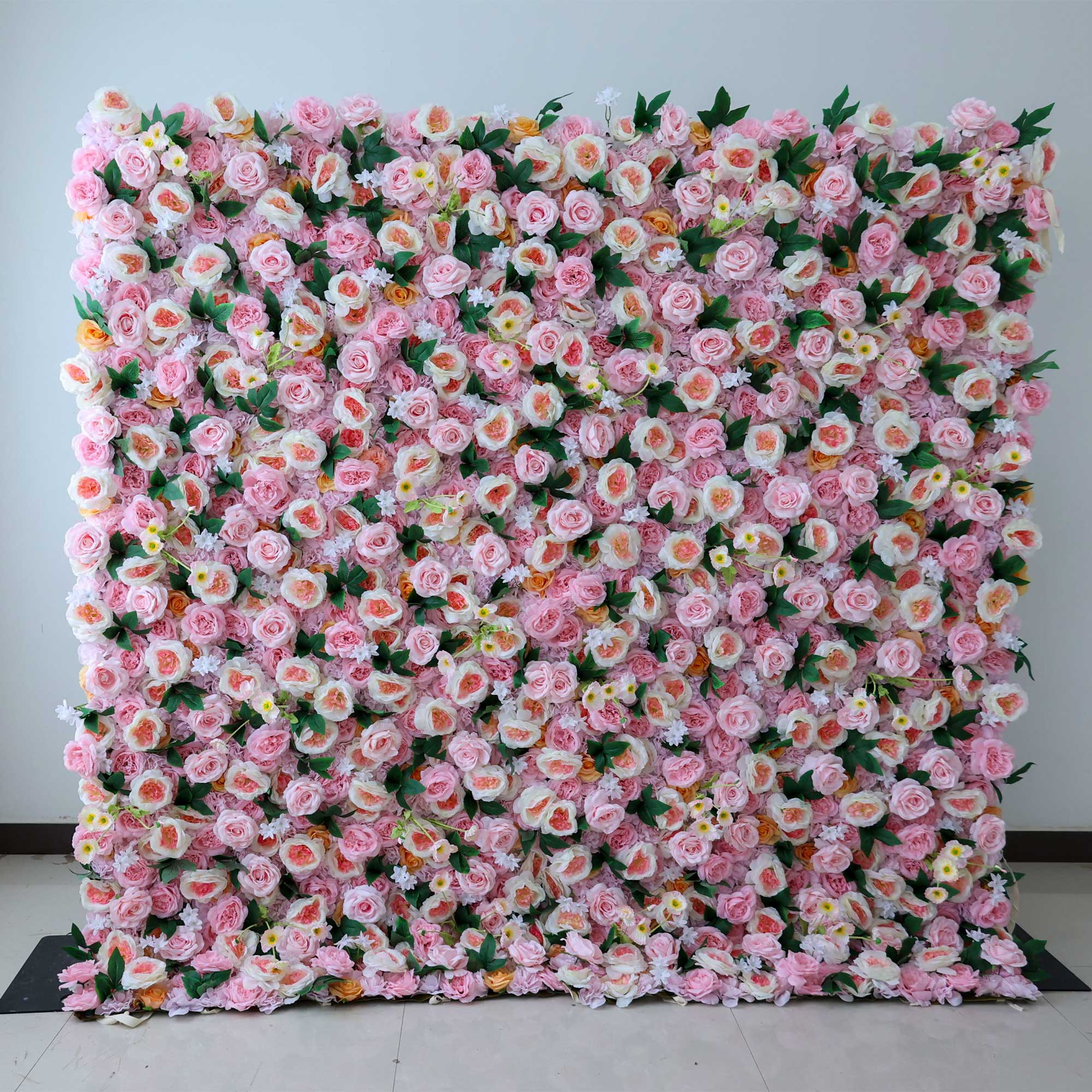 Handcrafted 5D artificial flower wall backdrop with soft pink and peach roses, accented with green leaves, set against a light background. Ideal for weddings, celebratory events, and photoshoots, adding a cheerful and inviting ambiance. VF-413-1