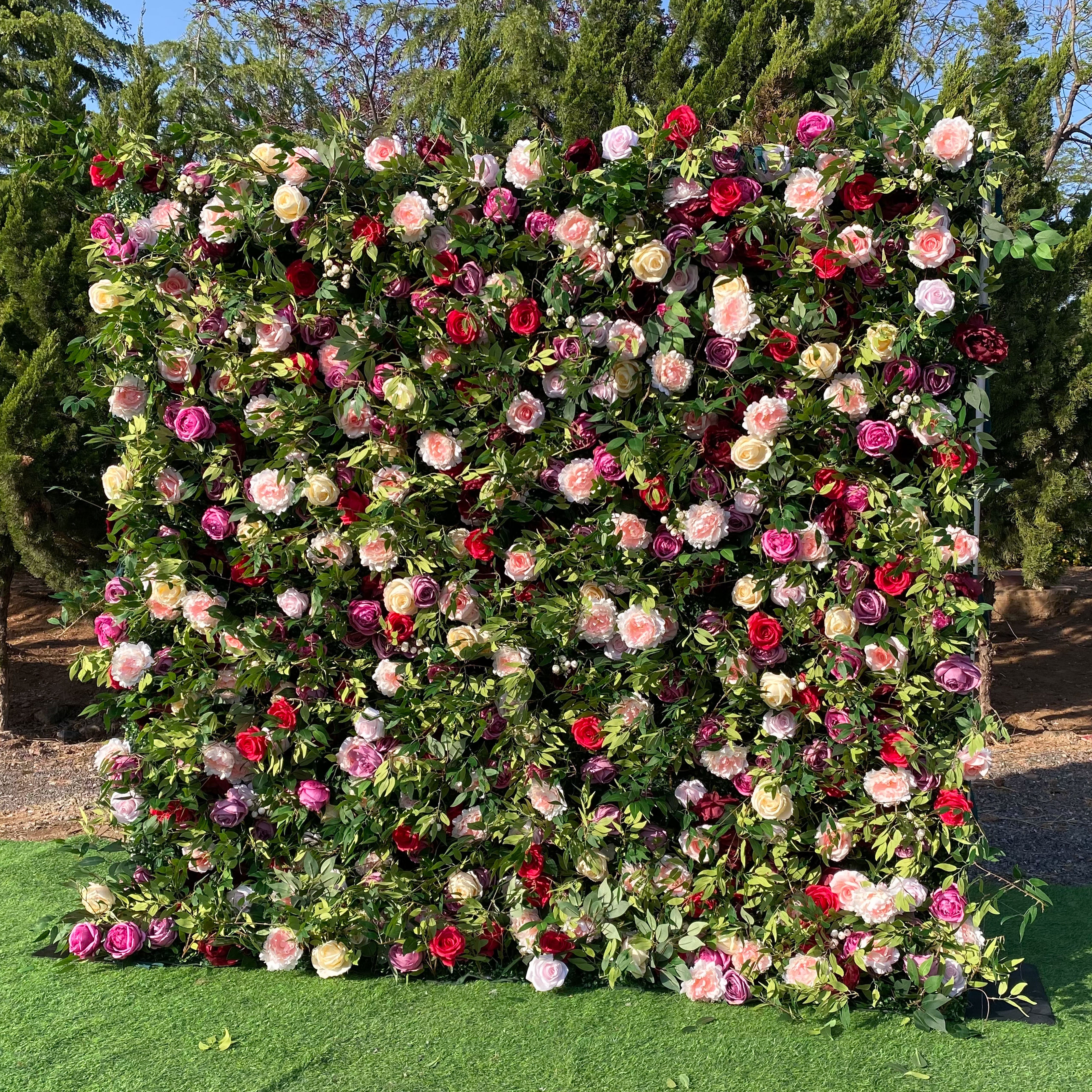 Valar Flower stunning flower wall with a combination of dark red, pink, and peach roses surrounded by greenery, creating a bold and sophisticated decor piece.