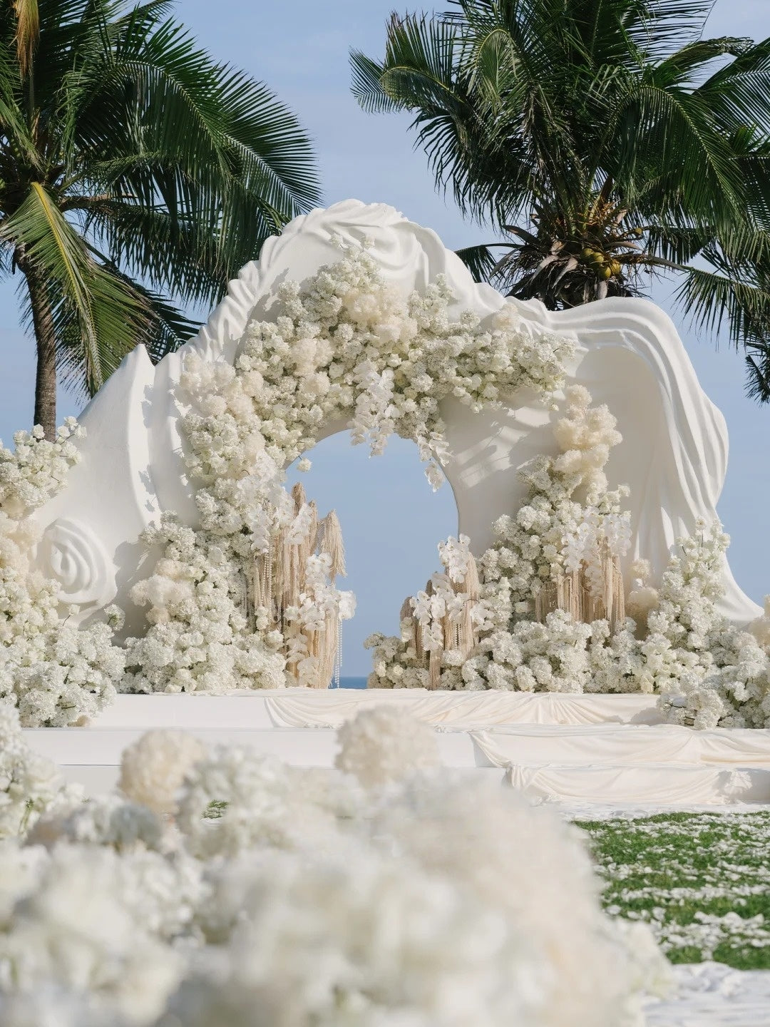 All-White Coastal Wedding Ceremony with Sculptural Floral Arch