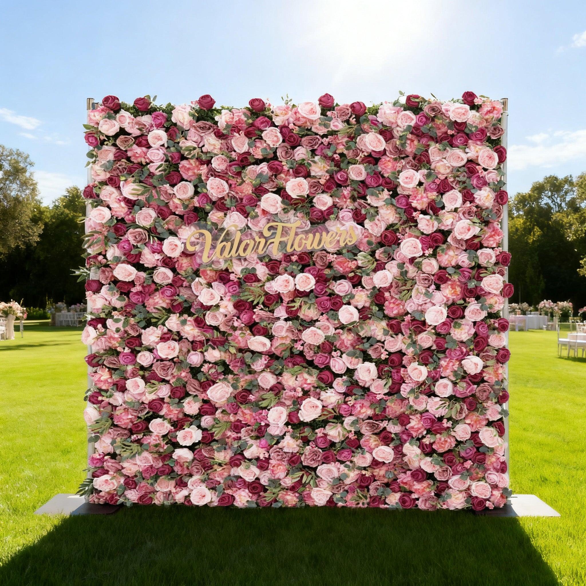 Floral wall with pink and white flowers and 'Valer Flowers' branding on a grassy field.