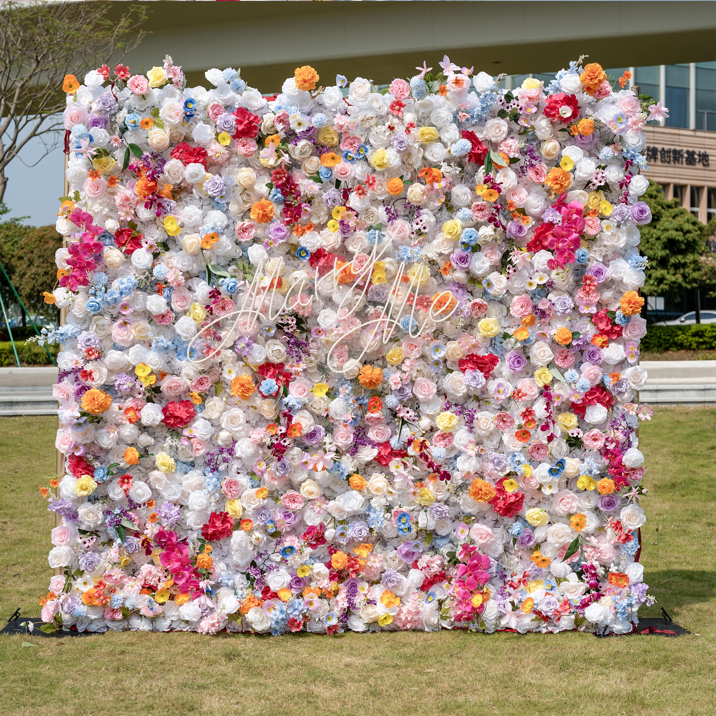 Floral wall with colorful flowers and 'Happy Birthday' text in an outdoor setting.