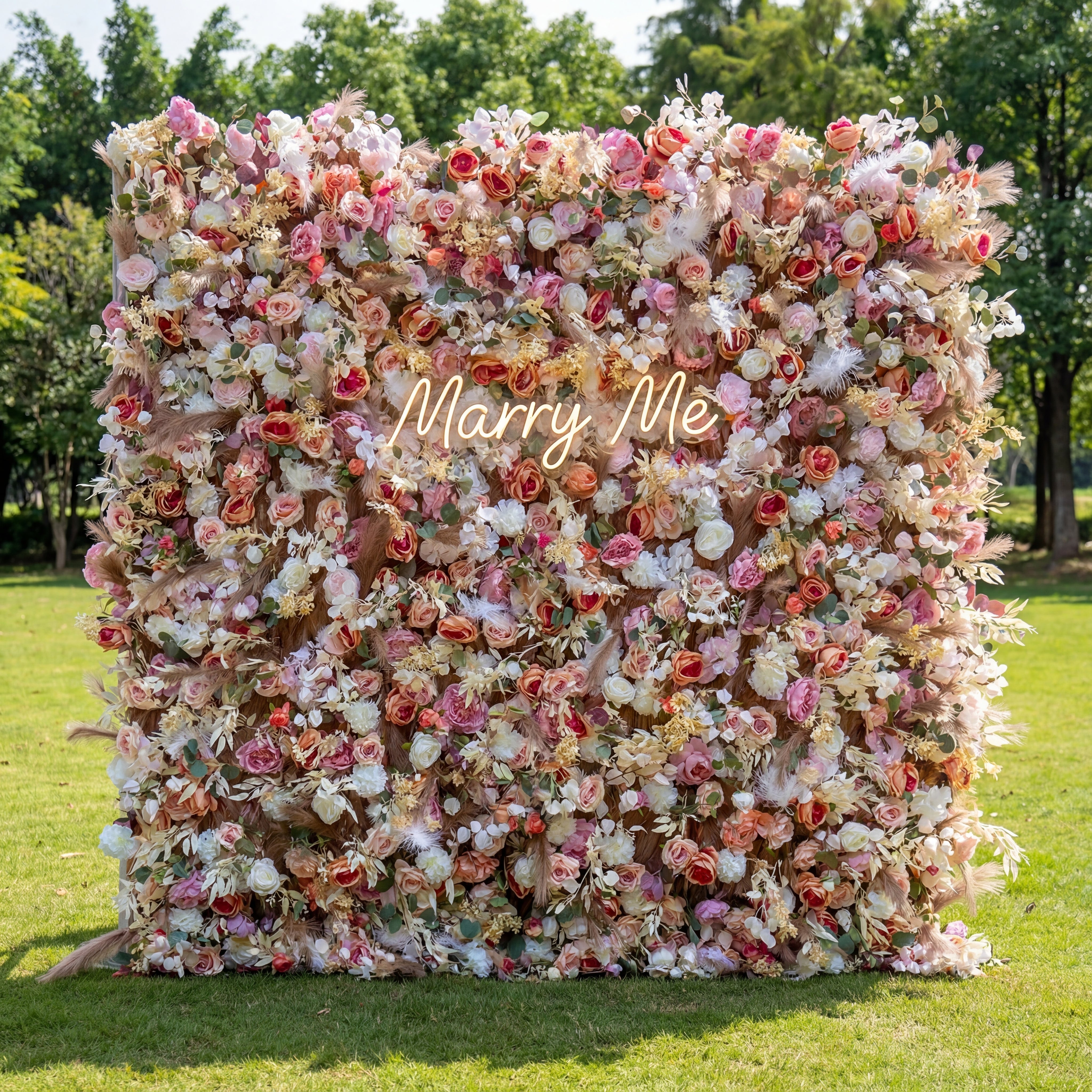 Floral wall with 'Marry Me' text in a park setting