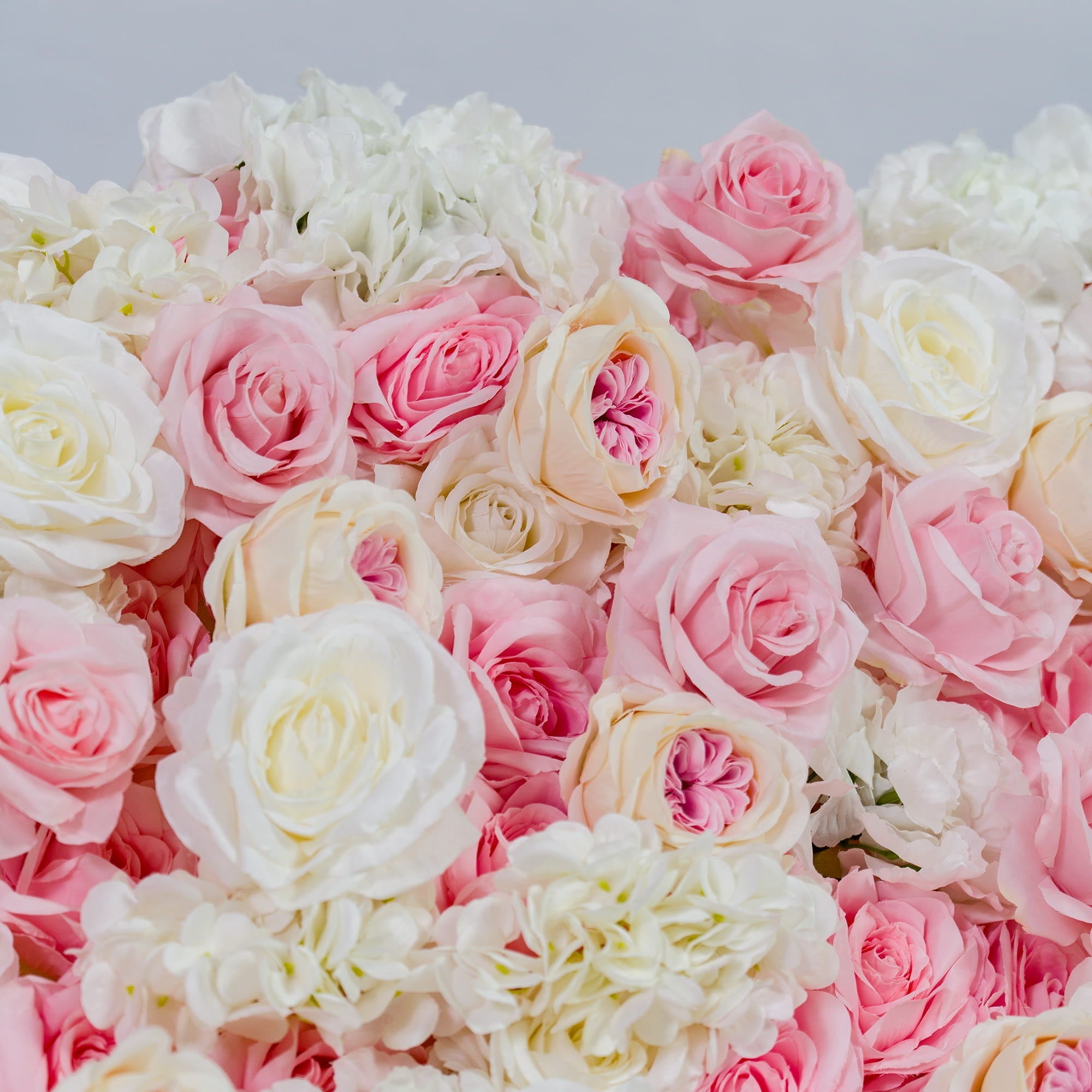 This photo showcases a dense floral arrangement featuring a mix of pink and white roses, along with white hydrangeas. The soft pastel color palette creates a romantic and dreamy atmosphere. Ideal for weddings, bridal showers, or other romantic events, it exudes an elegant and sophisticated style, perfect for adding a touch of charm to any occasion. 