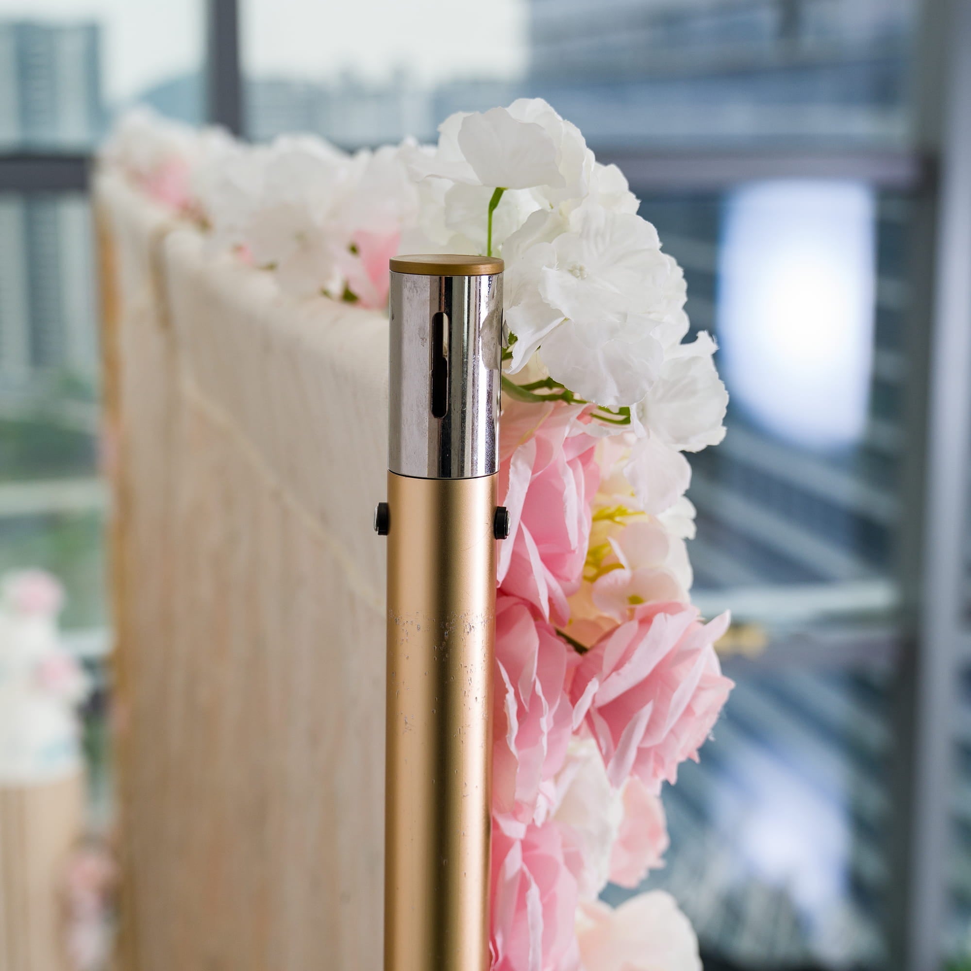 This photo shows a close - up of a floral backdrop setup. The backdrop features a mix of pink and white flowers, likely roses and hydrangeas, creating a soft and romantic aesthetic. It is attached to a golden pole, suggesting a decorative structure. Ideal for weddings, bridal showers, or other romantic events, it exudes an elegant and dreamy style with its pastel color palette. 