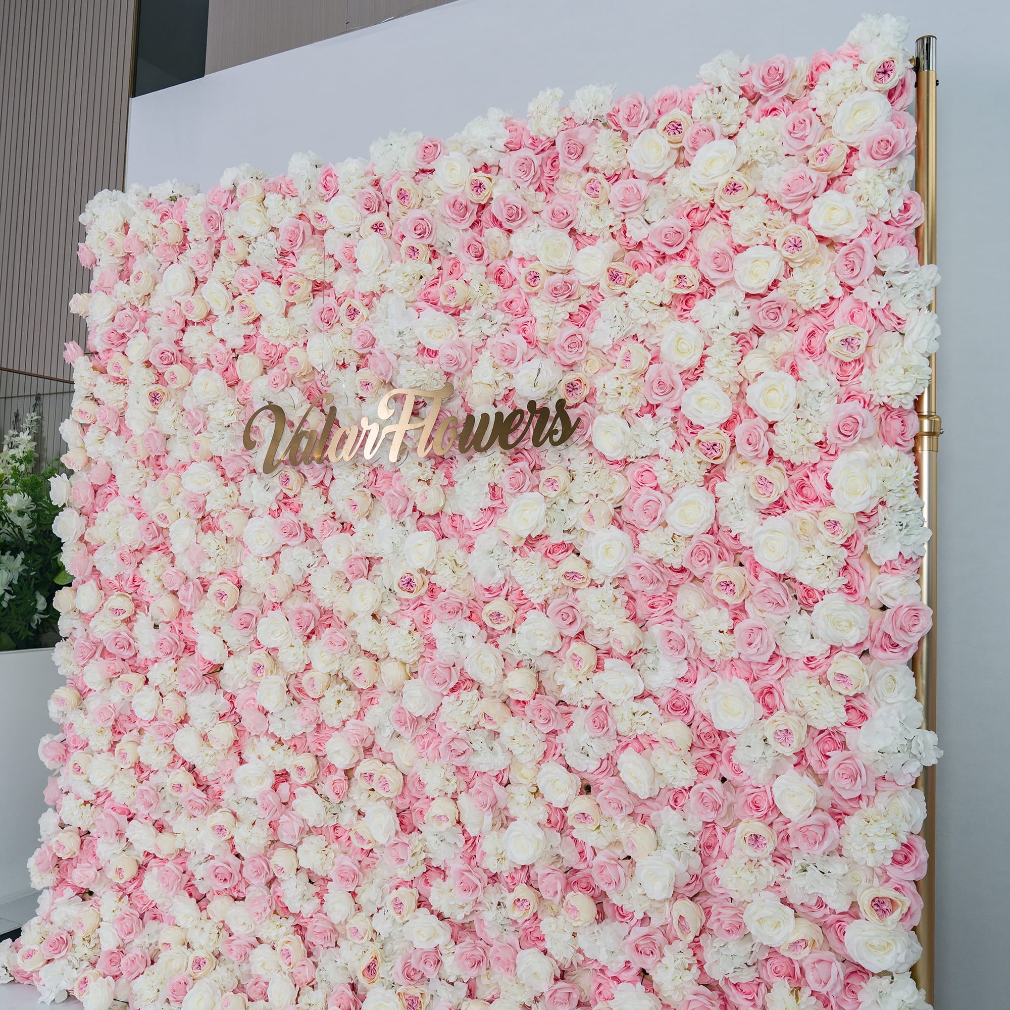 This photo showcases a lush floral backdrop densely covered with pink and white roses, creating a soft and romantic color scheme. The backdrop features the elegant gold text "Valar Flowers" prominently displayed. Ideal for weddings, bridal showers, or other romantic events, it exudes a dreamy and sophisticated style, adding a touch of elegance to any celebration. 