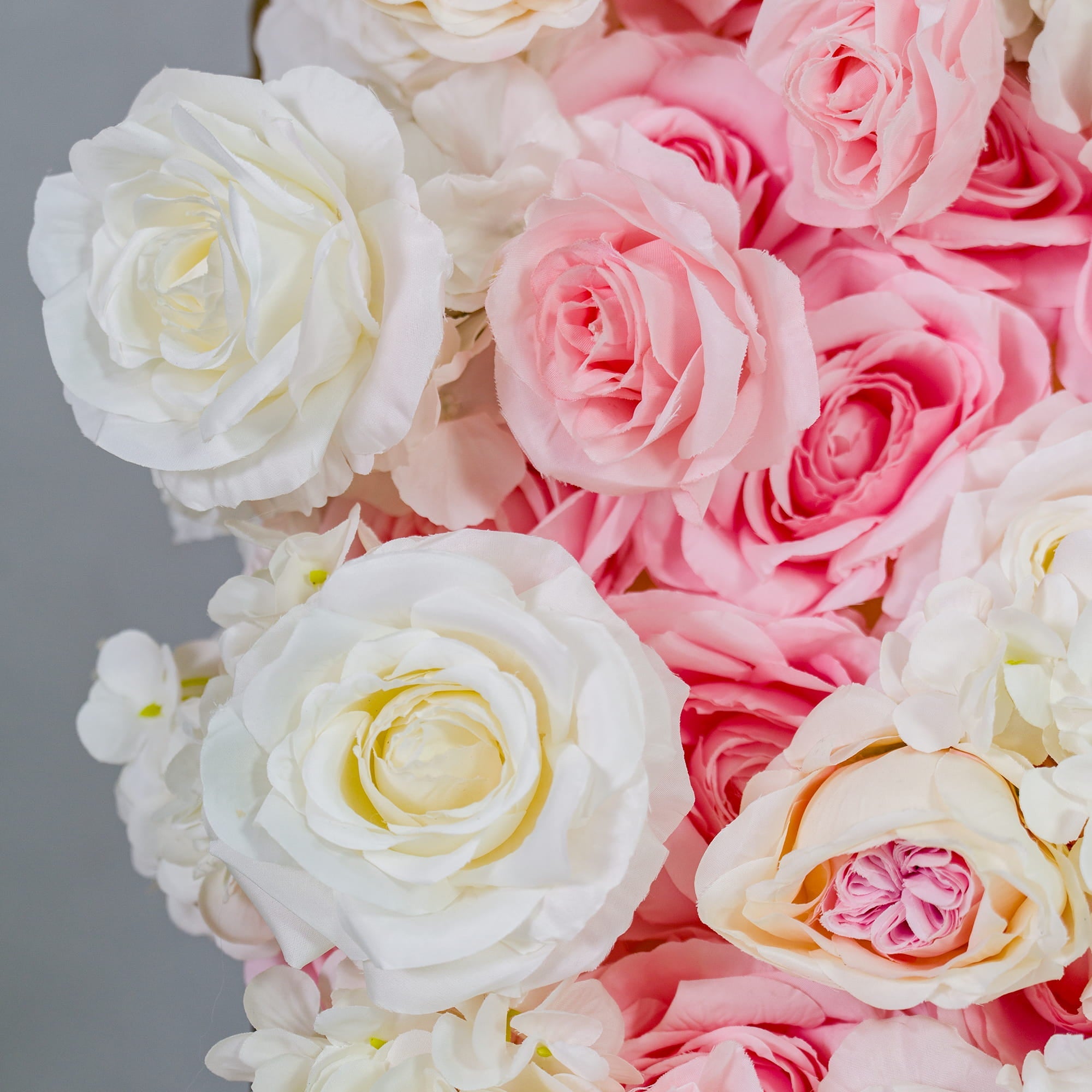 This photo showcases a dense arrangement of pink and white roses, creating a soft and romantic visual. The flowers are in full bloom, with varying shades that add depth to the display. Ideal for weddings, bridal showers, or other romantic events, this floral setup exudes elegance and charm, enhancing the celebratory atmosphere with its pastel color palette. 