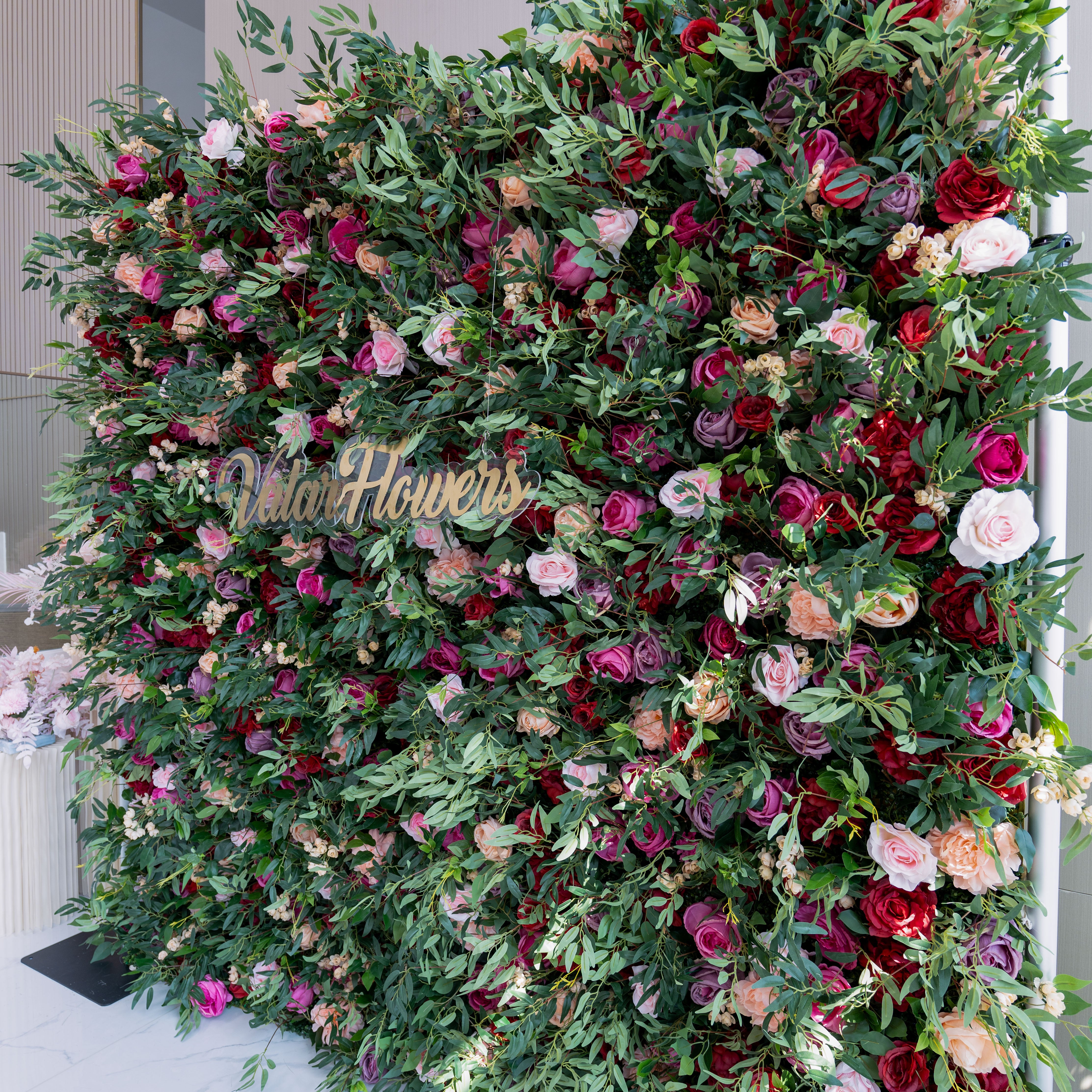 Luxurious floral backdrop filled with rich shades of red, purple, and soft pink roses, perfect for elegant events and indoor settings.