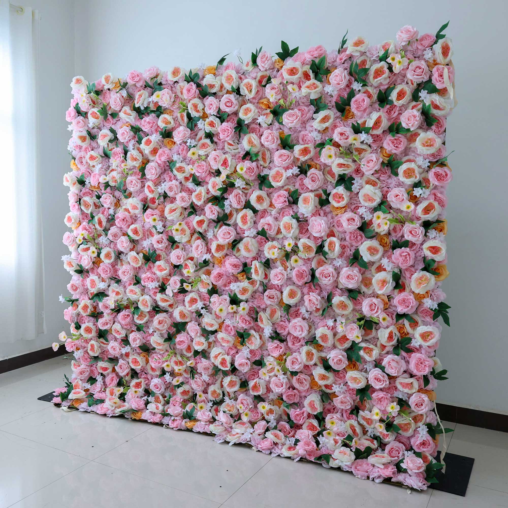 Handcrafted 5D artificial flower wall backdrop with soft pink and peach roses, accented with green leaves, set against a light background. Ideal for weddings, celebratory events, and photoshoots, adding a cheerful and inviting ambiance. VF-413-2