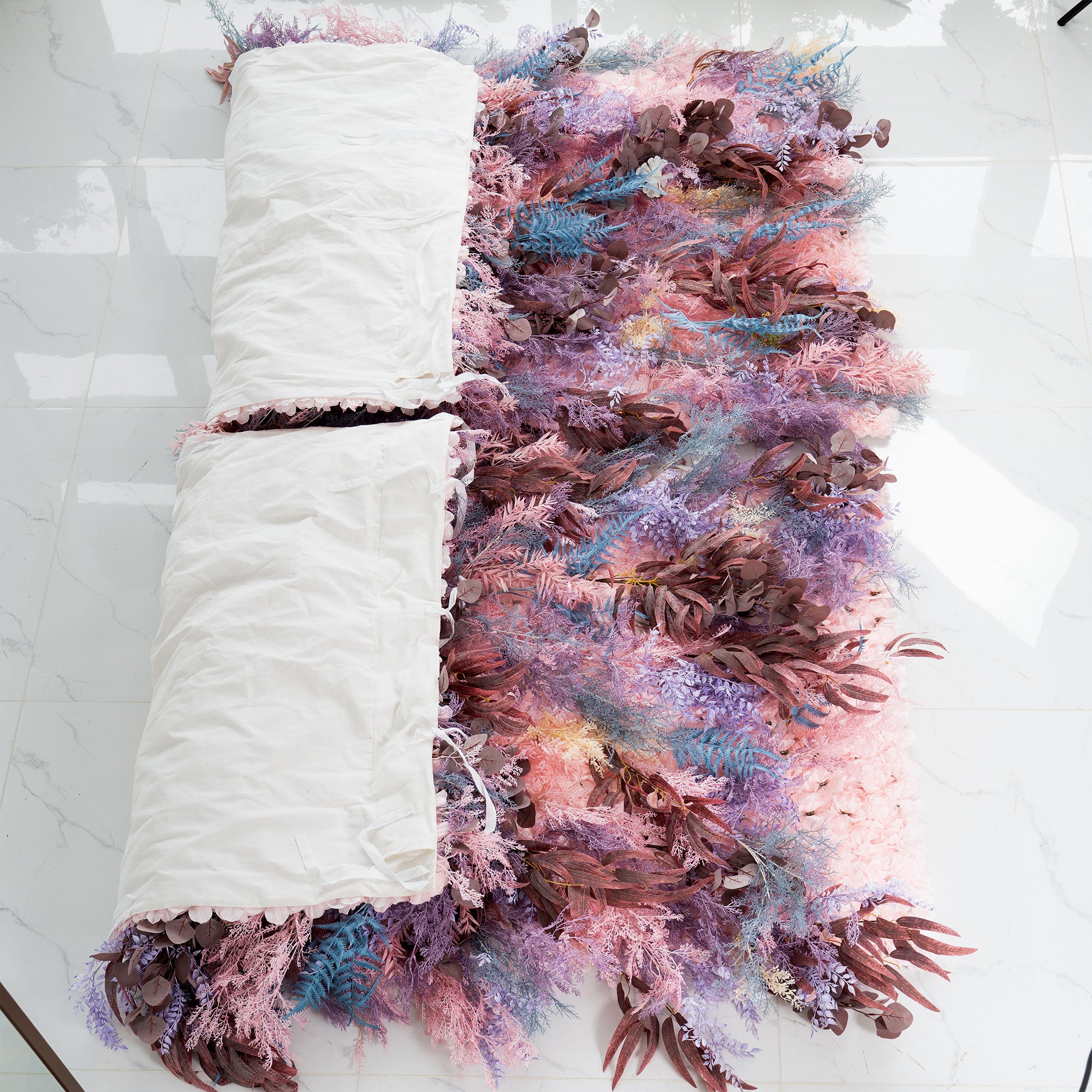 Whimsical purple and pink artificial flower backdrop wall with cascading leaf layers

