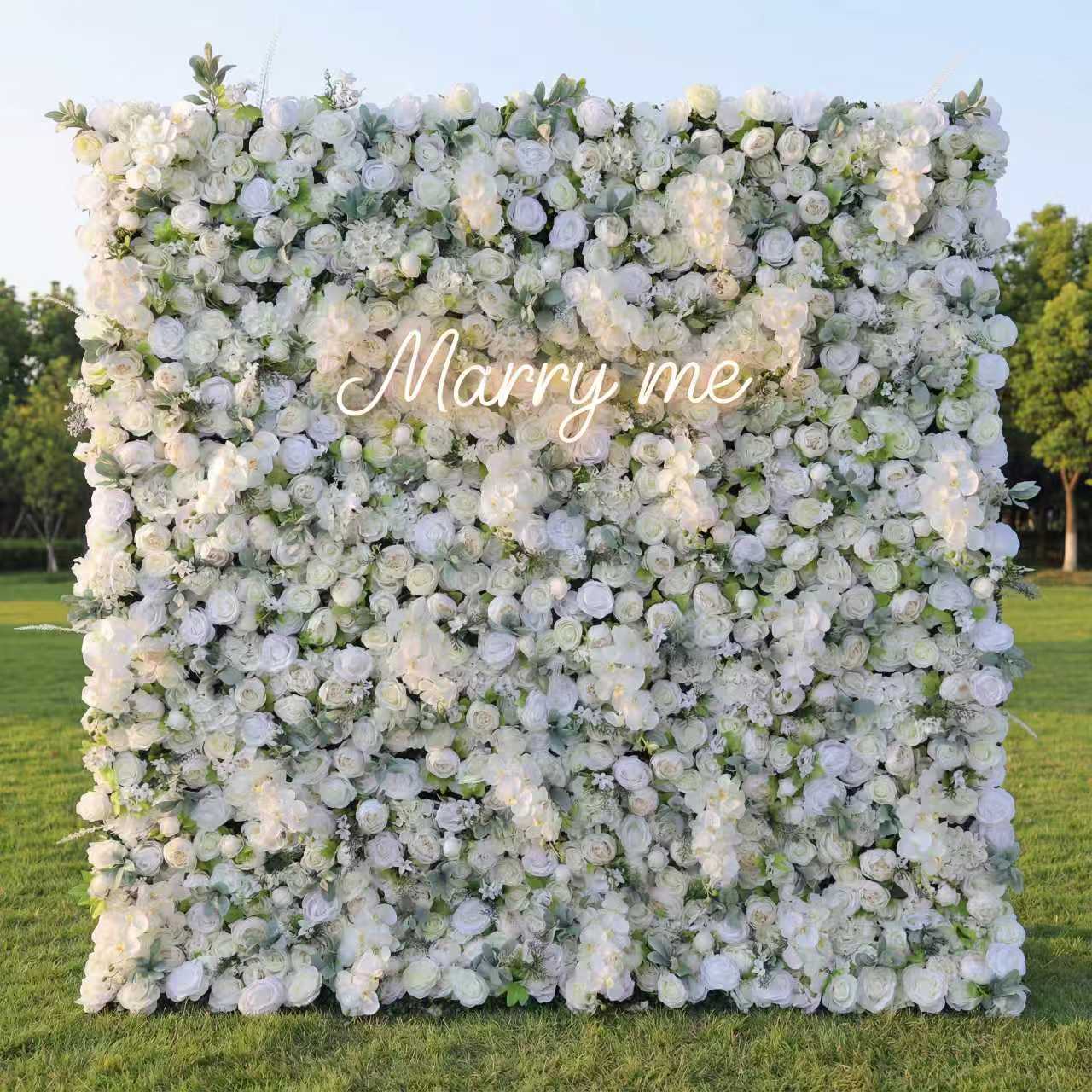 Floral wall with 'Marry me' text on a grassy field