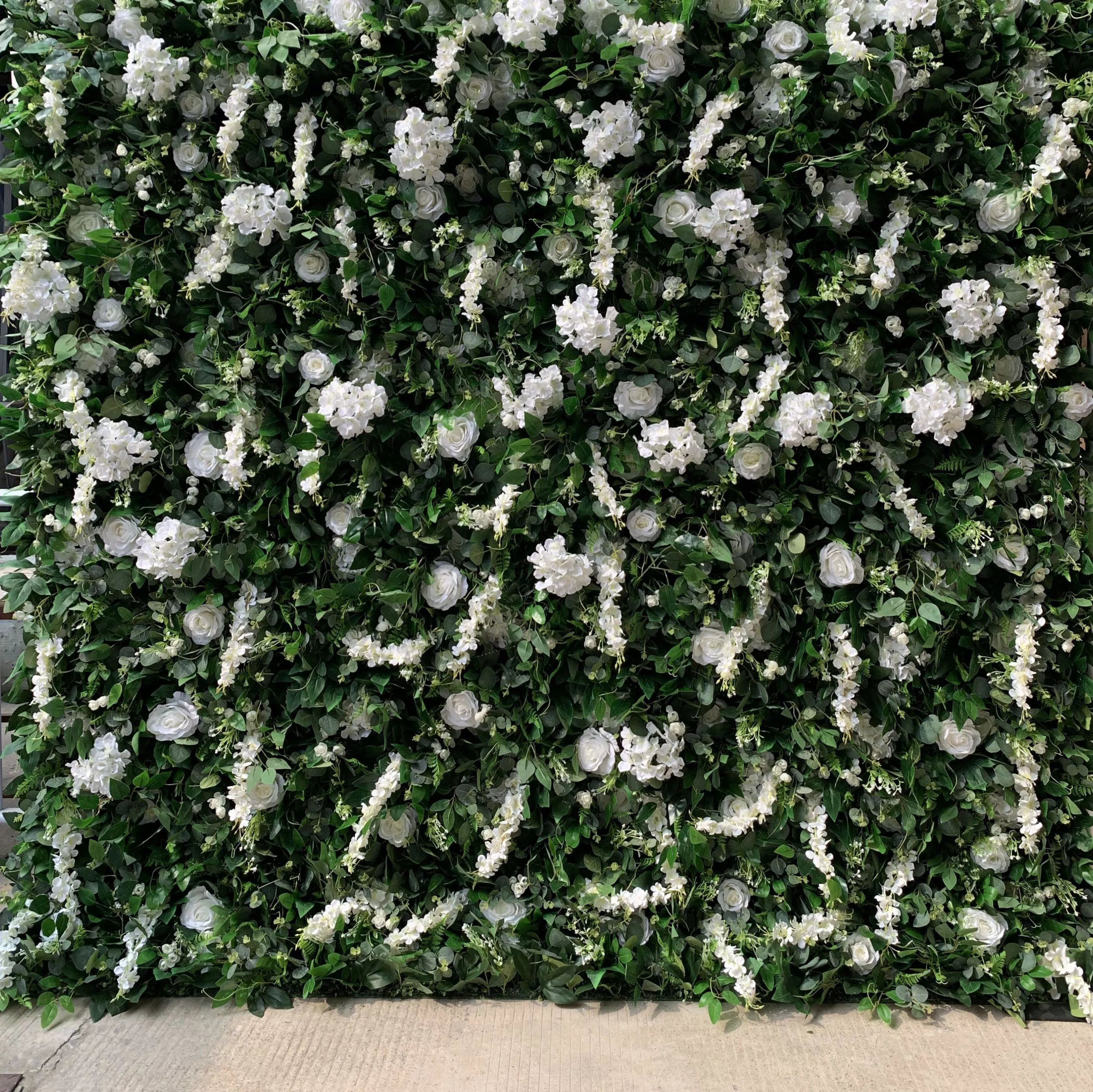 زهرة فالار تتدحرج من القماش الأبيض الصناعي وأوراق خضراء حية خلفية جدارية زهرية للزفاف ، ديكور حفلات زهور ، حدث